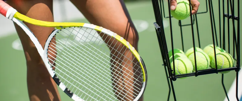 Tennis player taking balls from a ball basket
